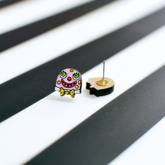 A small Mr Blobby stud earring featuring his face and bow tie, shown next to the other earring from the pair placed upside down to reveal the earring post on the back.