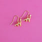 Gold plated brontosaurus dinosaur earrings with hooks on a pink background