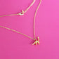 Gold plated necklace with a brontosaurus pendant on a pink background