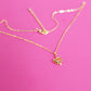 Gold plated necklace with a monstera leaf pendant, laid out with the fine chain and lobster clasp visible on a pink background