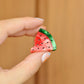 Hand holding a small watermelon hair claw clip against a wooden background